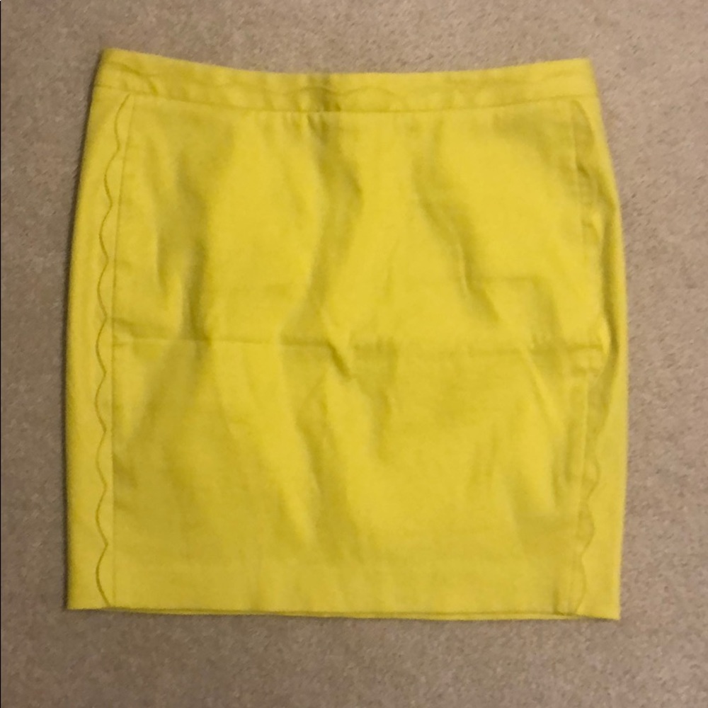 Yellow mini skirt with scalloped detail.